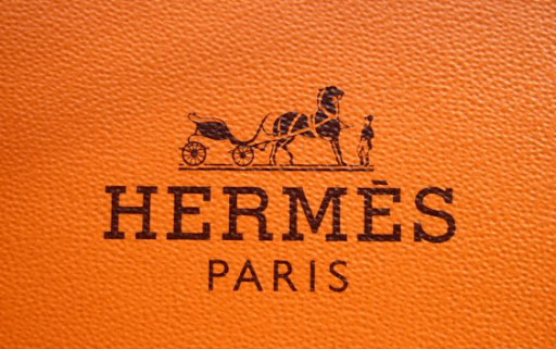 Logo Hermes với tên của người sáng lập Thierry Hermes, màu cam chủ đạo và cỗ xe ngựa
